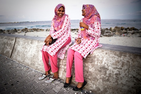 Two women sit on the sea wall that protects Male, Maldives